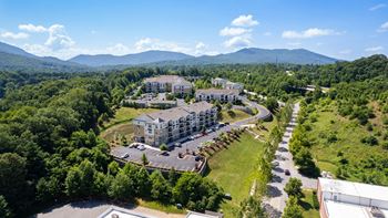 an aerial view of a building surrounded by trees and mountains